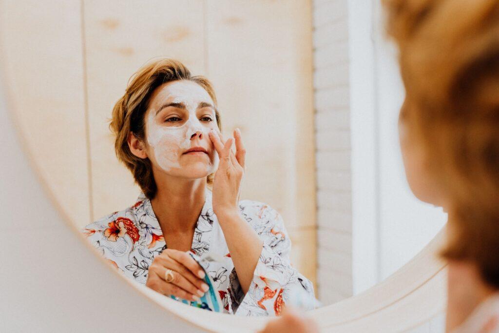 Frau macht sich eine Maske am Spiegel