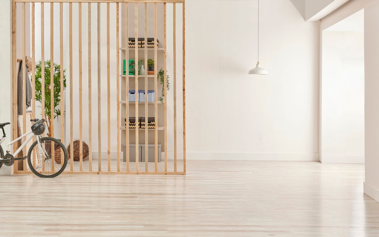 Minimalistischer Raumteiler aus vertikalen Holzstreben mit Regal und Fahrrad im hellen Loft – clevere Zonierung im Interior Design