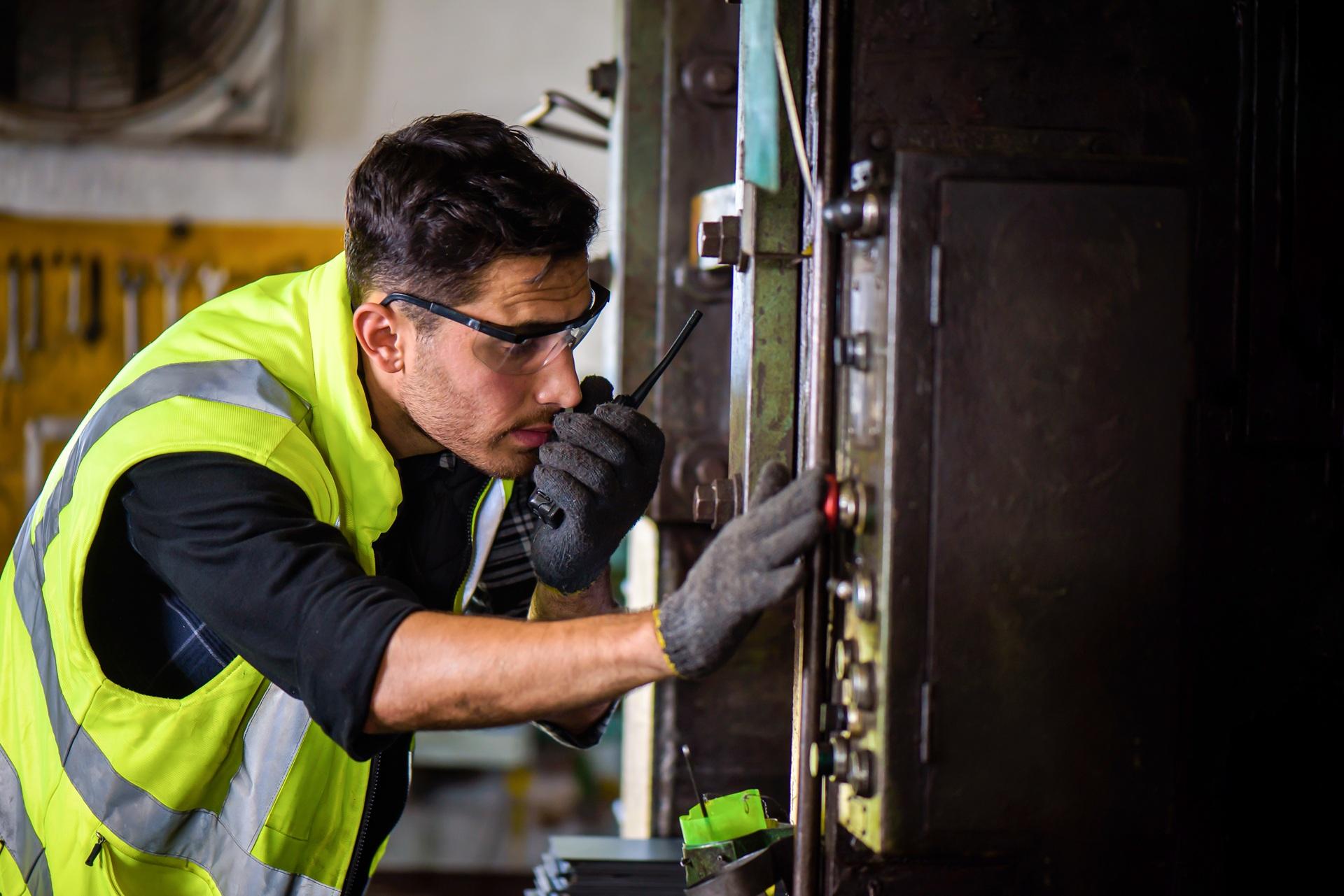 Arbeiter prueft Maschine mit Funkgerät im Werk | Förderschläuche