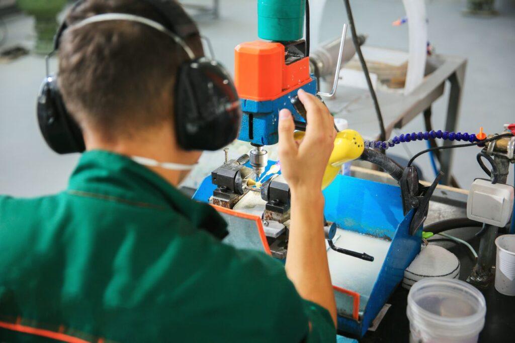 Ein Mitarbeiter in der Produktion bearbeitet ein Schmuckteil mit Spezialmaschine – Fertigungsprozess von schmuck bernd wolf